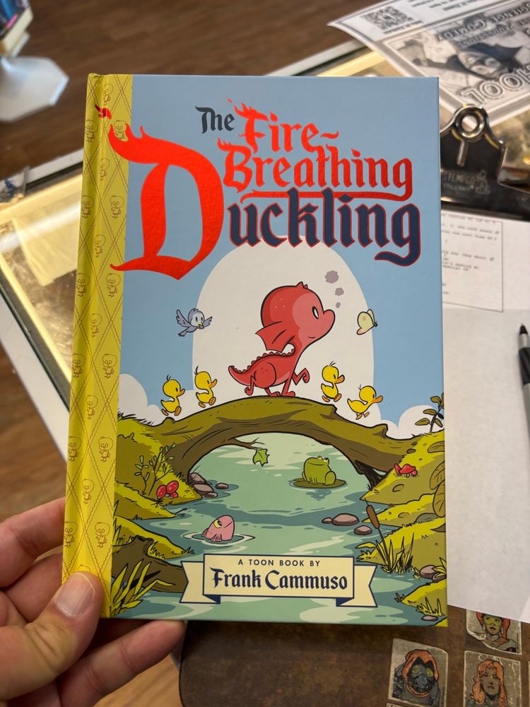 A book called ‘The Fire-breathing Duckling’ it shows what is obviously a baby dragon walking across a log that spans a stream, and is generally adorable.