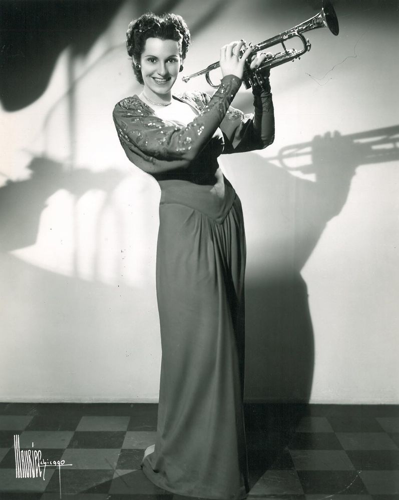 Joy M. Cayler standing in a gown holding her trumpet