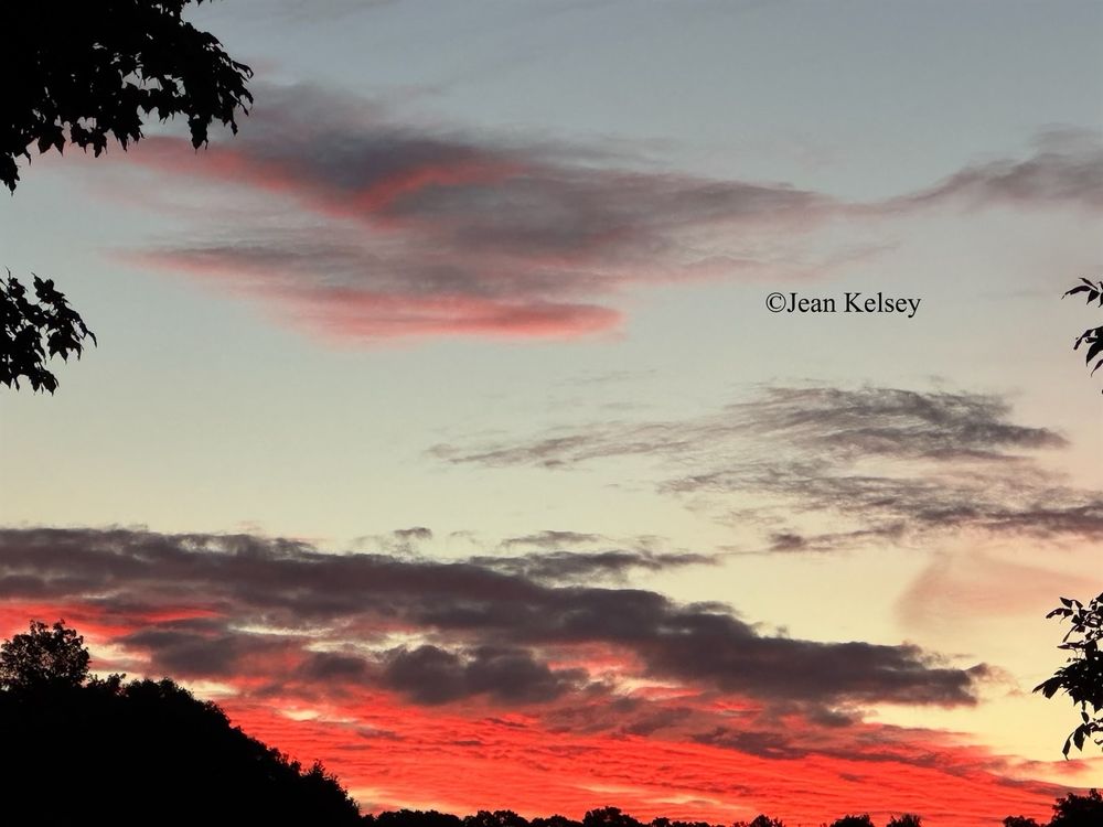Clouds closer to the sun are blasted with colors of bright orange mixed with some darker clouds.