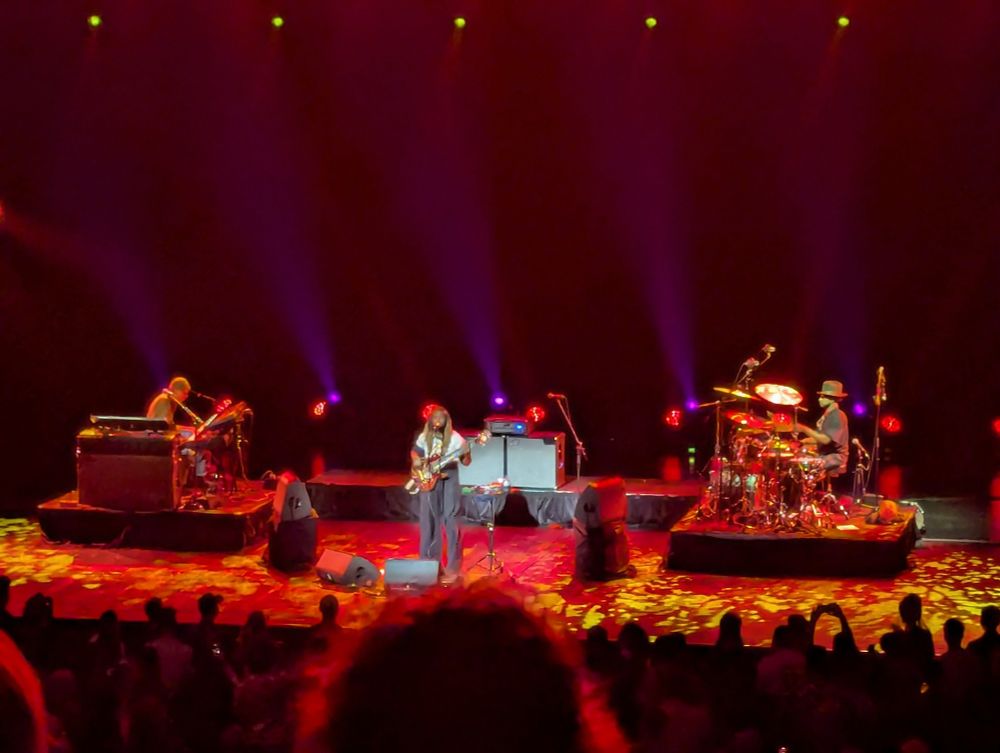 Bassist Thundercat plays on stage with backing keyboards and drums.