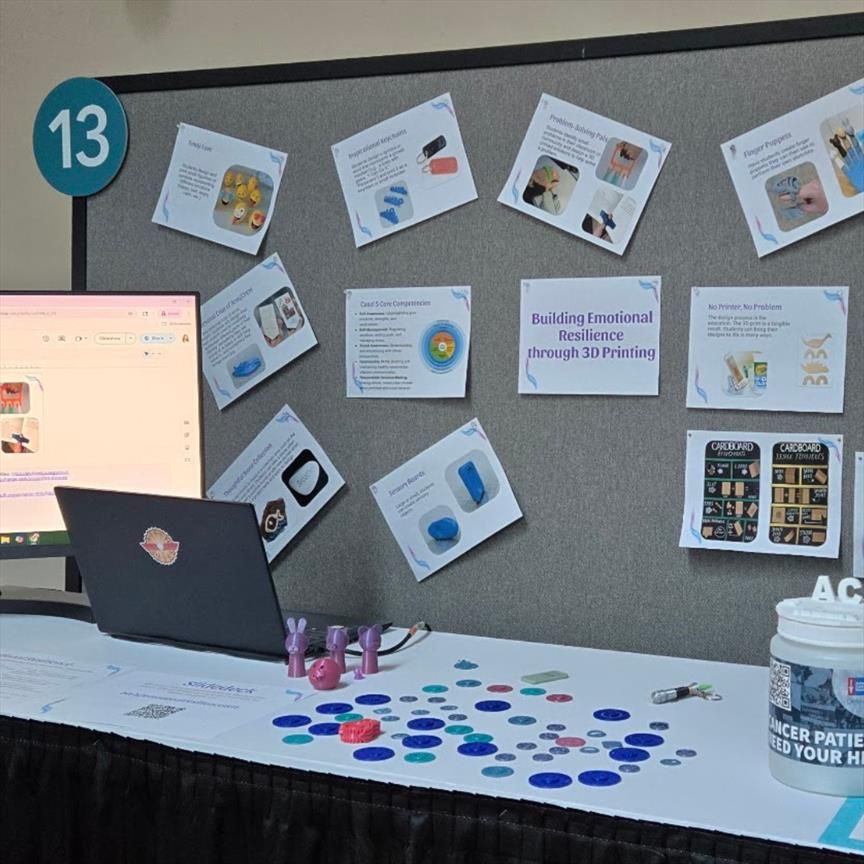 Poster session setup featuring printed slides displayed on a backdrop behind a table. Table includes 3D printed samples related to the presentation. Slide text is partially visible; full slide content and corresponding alt text available at bit.ly/emotionalresilienceISTE.

