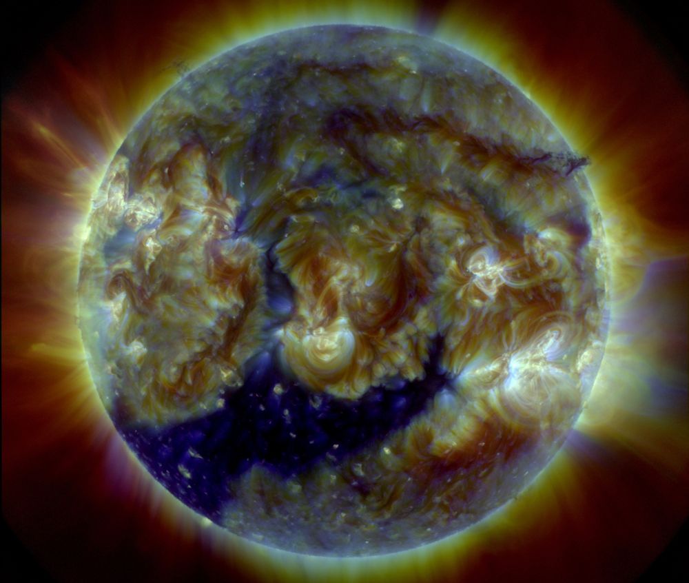 Die ganze erdzugewandte Seite der Sonne in verschiedenen Farben, vor allem in Braun- und Blautönen, die wild gemischt ineinander übergehen und das dynamische Geschehen zeigen. Aktive Gebiete sind heller und fast weißlich dargestellt. Um die Sonne herum ein Kranz aus Strahlung.