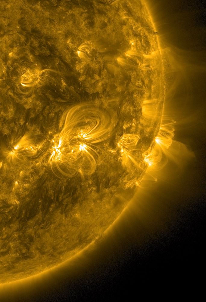 Der rechte Rand der erdzugewandten Seite der Sonne in gelber Farbe. An drei bis vier Stellen haben sich koronale Loops gebildet, die entlang der Magnetfelder weit ins All und zurück zur Oberfläche reichen. Sie sehen wie dünne, hell leuchtende und gebogene Fäden oder Drähte aus, also sehr fein strukturiert und geformt.