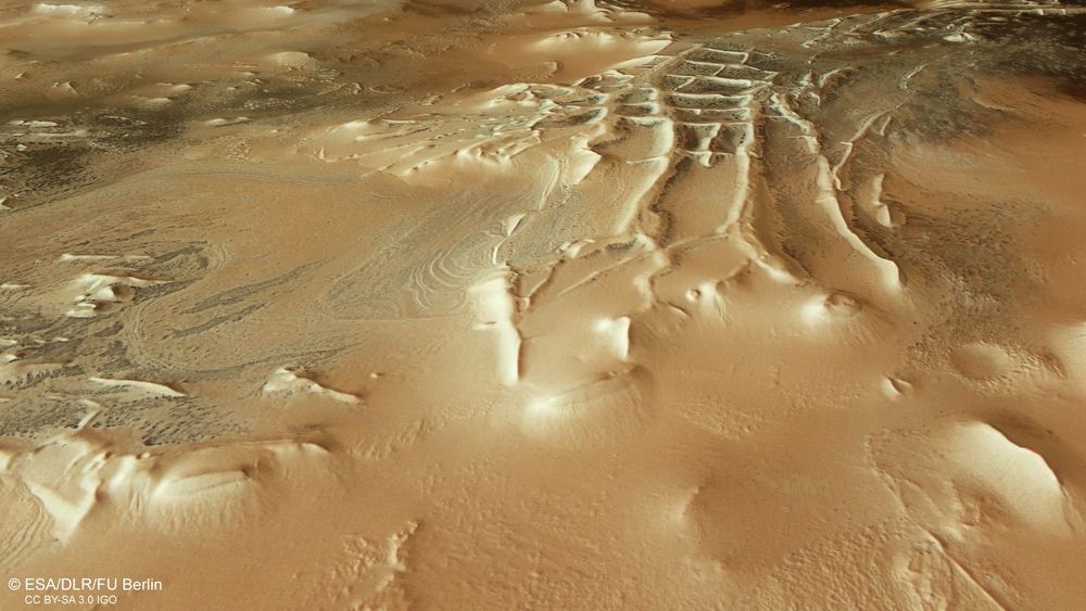 Eine Marslandschaft von oben gezeigt. Auffällig sind einige Wälle, die rechteckig geformt wie Wände eingestürzter Gebäude aussehen, wobei es sich natürlich nur um die Folgen geologischer Prozesse handelt.
