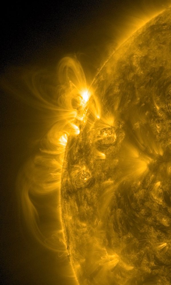 Der Bereich links oben auf der erdzugewandten Seite der Sonne in gelber Farbe. Auf der Zeigerposition zehn Uhr zwei bis drei weiße Stellen, von denen sogenannte koronale Loops ausgehen und zur Sonne zurückreichen. Das sind Bögen aus Sonnenmaterie, wobei es sich natürlich nicht um feste Materie handelt, wie wir die kennen. Sondern um ein Gas, genauer um ein Plasma. In diesem Zustand haben die positiv geladenen Atomkerne keine negativ geladenen Elektronen mehr, die sie umkreisen. Dadurch - keine Sorge, die kleine Physikstunde ist gleich vorbei - ist die Sache nicht mehr elektrisch neutral, wie das bei Atomen sonst der Fall ist. Sondern die Kerne sind eben elektrisch geladen und reagieren daher auf die komplexen Magnetfelder der Sonne, die diese Materie wie in Schläuchen gefangen halten. Und so kommt es zu diesen spektakulären Bögen, die sich auch hier im Bild vielfach überlagern und derart groß sind, dass die Erde da mehrfach hineinpassen würde. Spektakuläre Physik!