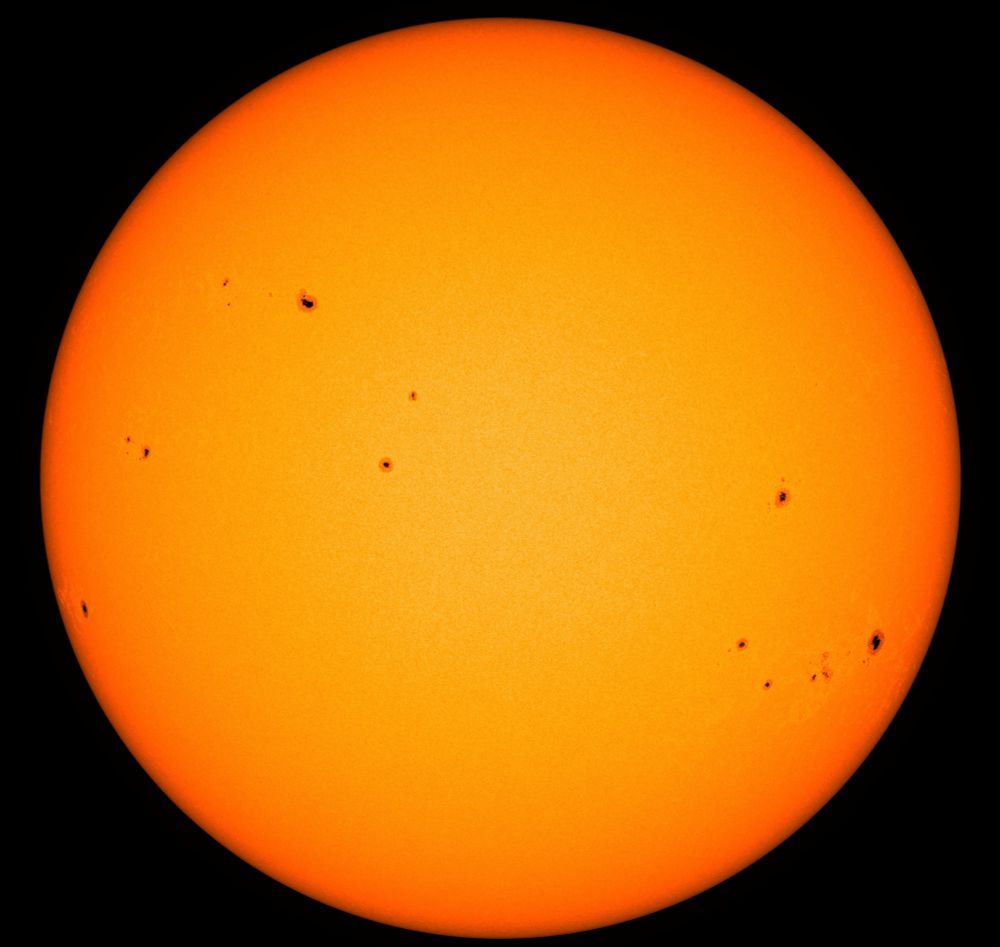 Die ganze erdzugewandte Seite der Sonne in gelber Farbe, am Rand leicht in orangerote Töne übergehend. In dieser Darstellung sind keine Strahlen oder andere Phänomene aus der Atmosphäre der Sonne zu sehen, sondern sie zeigt quasi direkt die Oberfläche - und zwar heute in einer etwas ungewöhnlichen Optik: Denn da sind zahlreiche Sonnenflecken als dunkle Punkte erkennbar, die anders als üblich nicht auf wenige Gebiete in Gruppen konzentriert, sondern an vielen Stellen verstreut sind. Davon mal abgesehen sind Sonnenflecken eine ganz normale Erscheinung. Sie entstehen durch Störungen in den lokalen Magnetfeldern der Sonne, die den Transport der Energie von innen nach außen behindern. So kommt es zu diesen Gebieten geringerer Temperatur und Helligkeit, wobei die Darstellung in Form dunkler Punkte täuscht: Auch diese fast schwarz wirkenden Flecken sind eigentlich gleißend hell, werden nur wegen der noch viel helleren Umgebung überstrahlt und deshalb so dunkel wiedergegeben.
