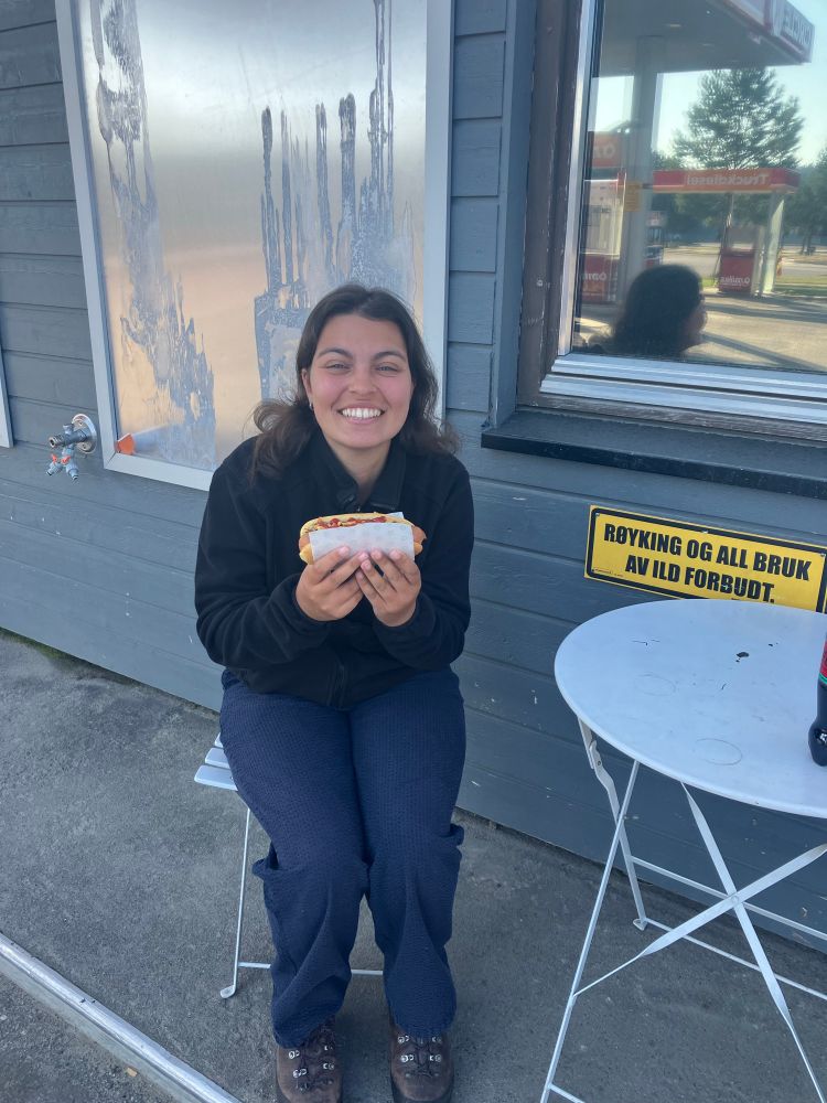 Trying the famous Norwegian petrol station hot dogs in Karasjok. Woman smiling holding hot dog!