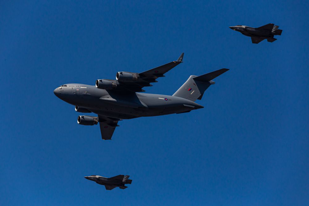 C-17 Globemaster with 2 F-35 jets on the wing in blue clear skies