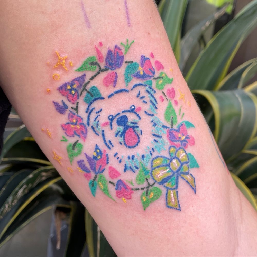Colorful crayon-style tattoo of a white dog in a frame of leaves and bougainvillea 