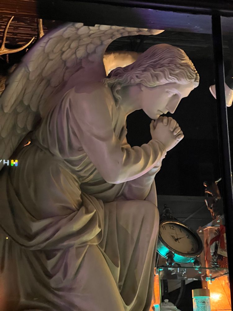 humanoid angel statue hands clasped under chin pose like thinking man statue 
