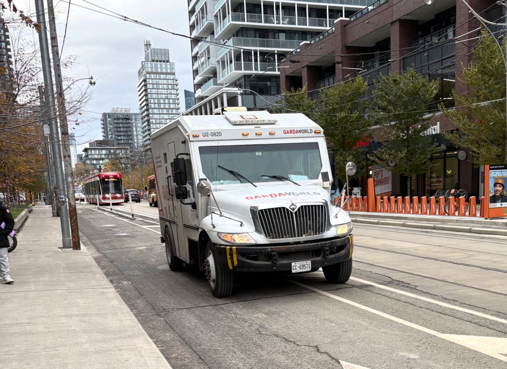 At the corner of River and Dundas in Toronto at 2 pm on Thursday, November 13, 2025, the two meatheads responsible for a Garda World armoured truck decided that the bike lane in front of the Rabba store was the best place to park their jalopy while they serviced the ATM inside. The vehicle is to the far left of the lane, which I’m sure the driver would use to excuse his intransigence by saying cyclists would have plenty of room to get around. Unfortunately, there is a 505 streetcar in the background, and moments later it will be stopped to discharge and take on passengers, right where this truck is parked, therefore blocking the doors. Just part of the passing parade in Toronto. 