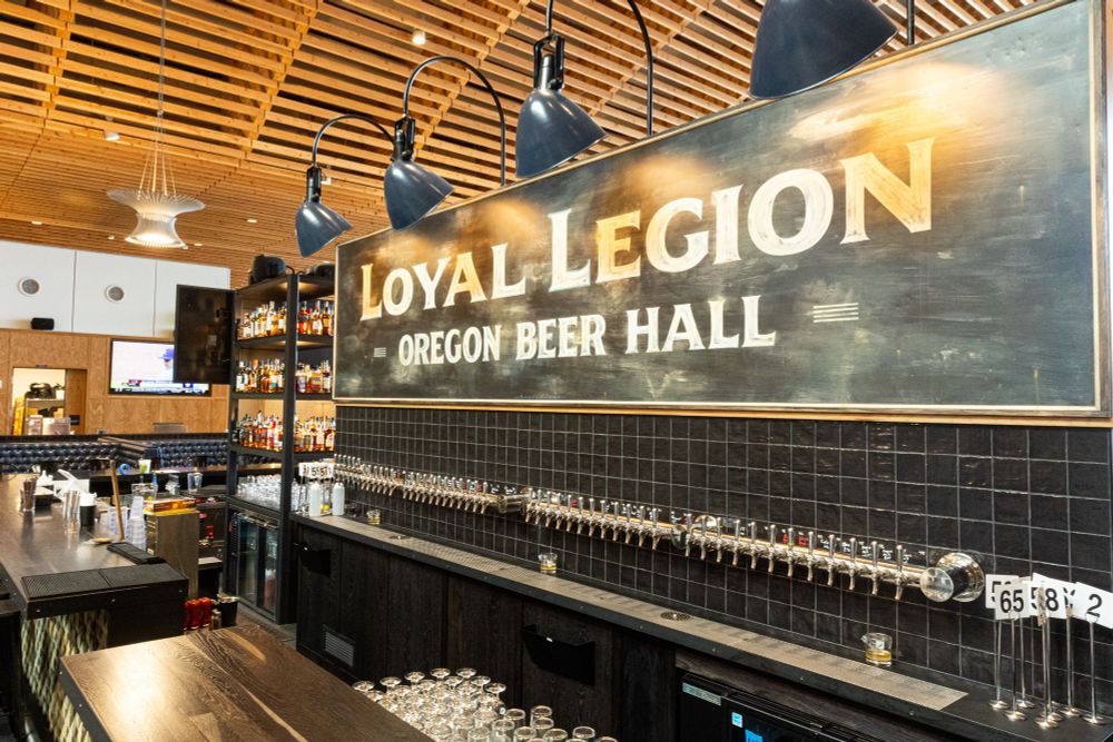 Bar with tap handles and sign that says Loyal Legion Oregon Beer Hall