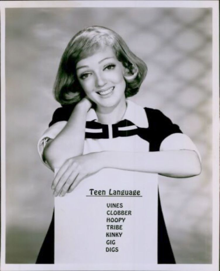 A 1968 photo of actress Genadee Cook holding a sign with "teen slang" written on it, including the word "hoopy"