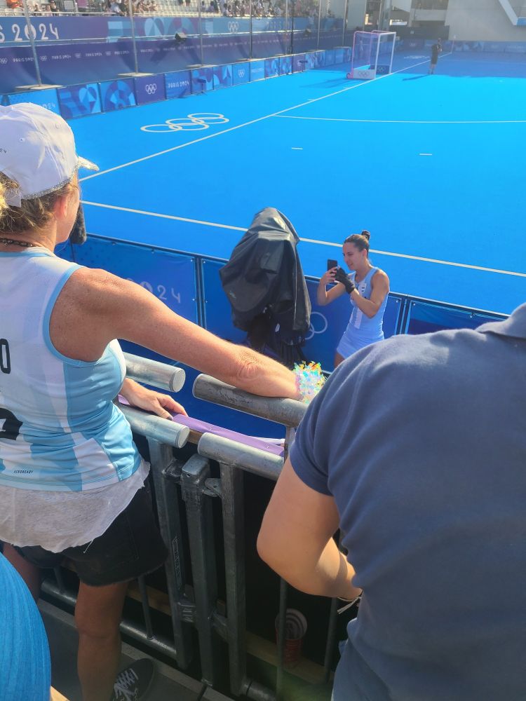 An Argentinian field hockey player taking pictures of the parents greeting her from the stands.