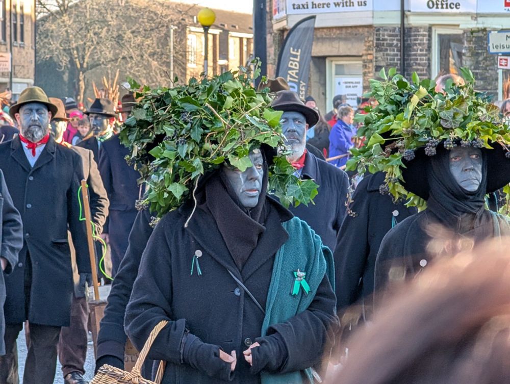 People dressed up with leafy costumes with their faces painted blue. 
