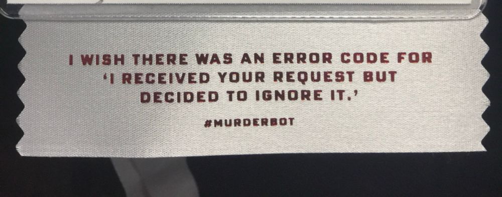 Badge ribbon from a science fiction con with quote from Murderbot, in all caps: I wish there was an error code for ‘I received your request but decided to ignore it.’