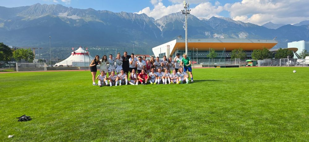Jubelnde Spielerinnen in weißen Trikots, im Hintergrund Bergmasiv
