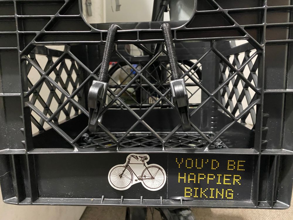 Stickers on black milk crate attached to an e-bike 