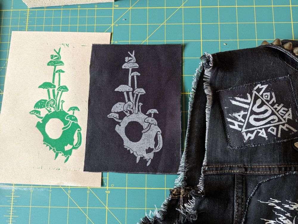 A side by side comparison of linocut print on paper and on fabric next to a block printed patch done with rubber on fabric.