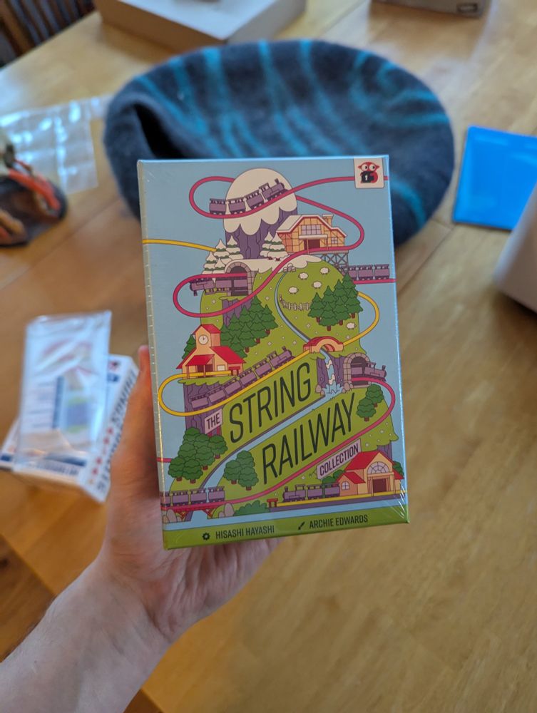 A small board game box with colorful art work and the name String Railway on it