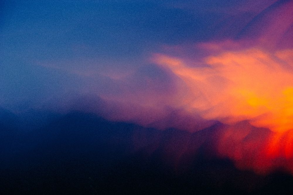 a total abstract, soft waves of color, it’s like a blue field (with just the hint of darker mountain silhouettes) being speared from the right side of the frame by a flaming feather of a phoenix 