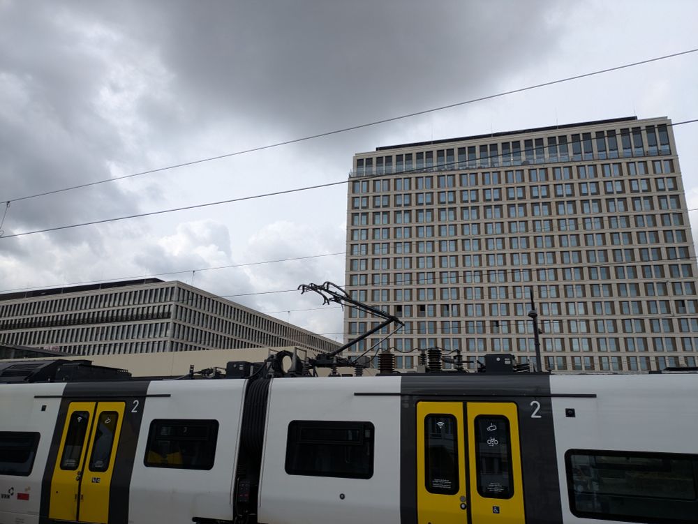 S-Bahn am Bahnhof einer deutschen Stadt mit Kastenform Häusern unter grauem Himmel 