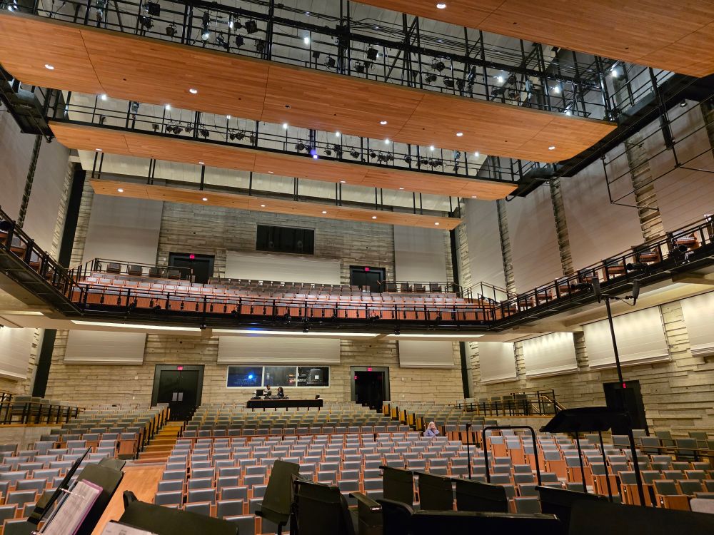 The empty Moody Performance Hall in Dallas Texas with lights up -  In the foreground are empty seats and folded stands waiting for performers downstairs. The empty hall holds the promise of 750 seats.