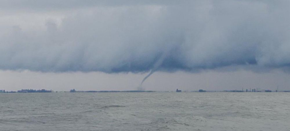 A tornado waterspout out in the distance over gray, chilly water
