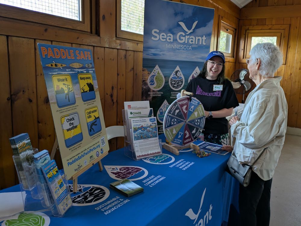 Abby Haugen smiles with a member of the public at a Minnesota Sea Grant table at the Minnesota Point 50 Turning Point event. Image credit: M. Rodman/MNSG.