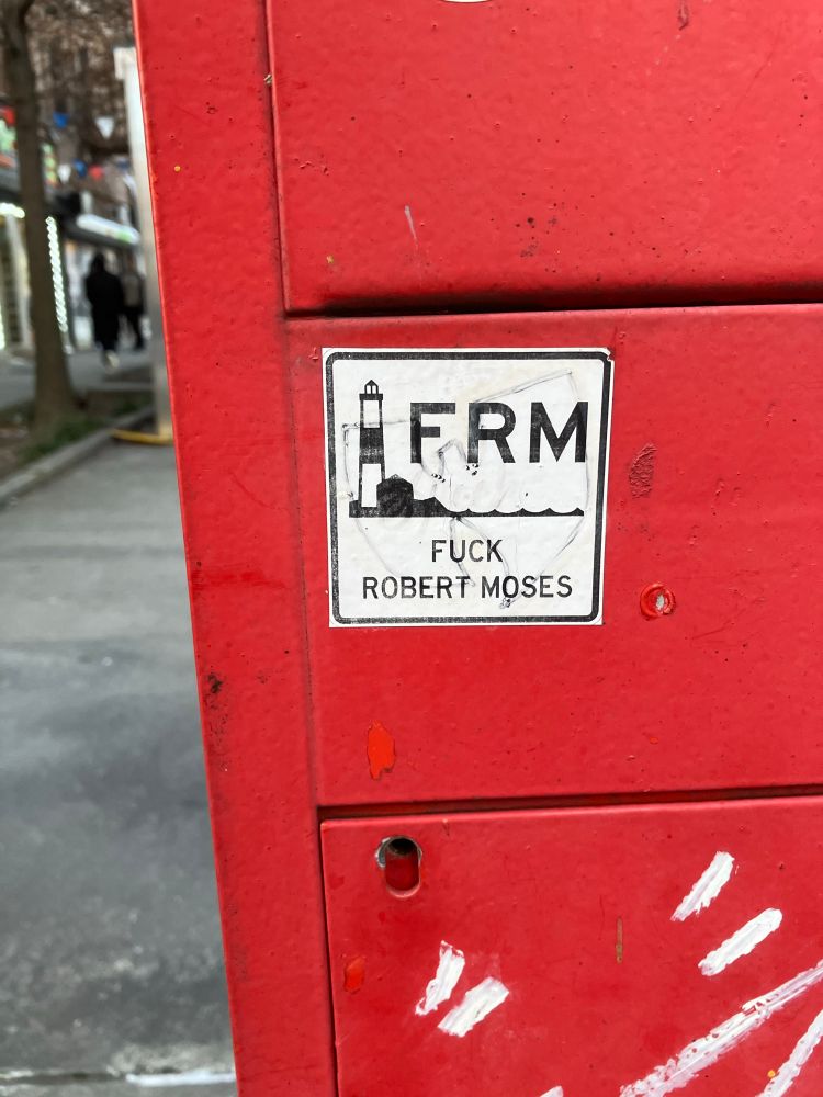 A “fuck Robert Moses” sticker in the style of a ocean parkway route sign 