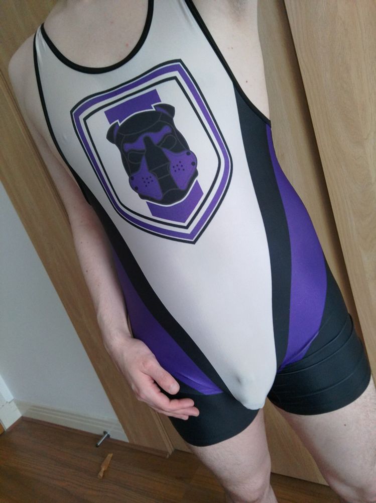 Front-facing purple, black and white wrestling singlet with an outline of a chastity cage.