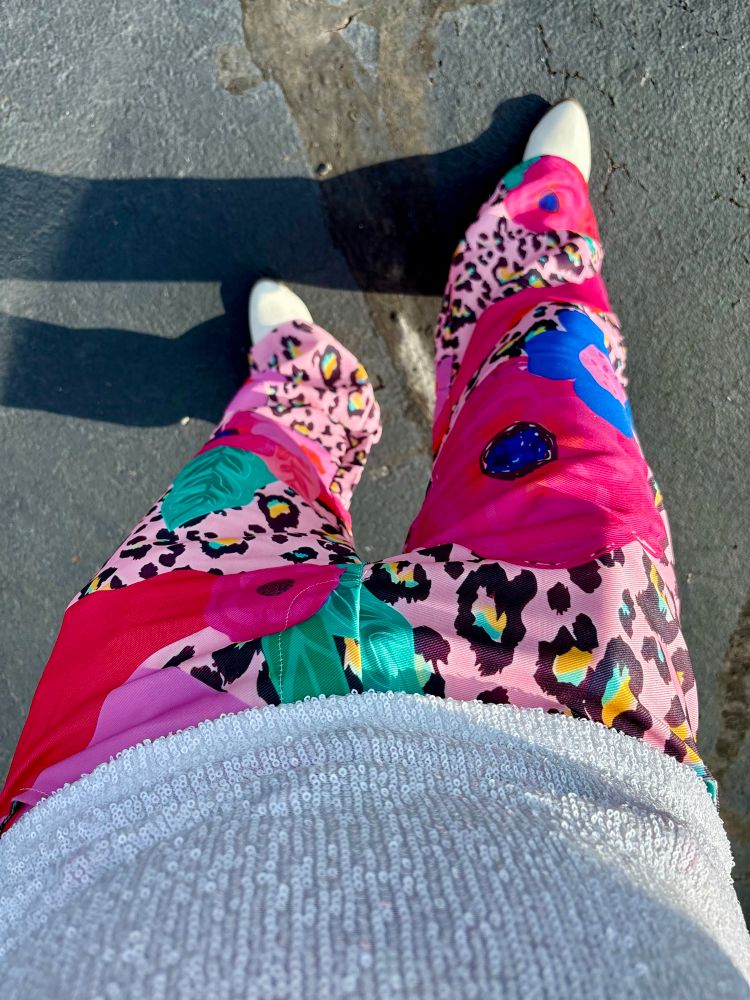 KP wearing pink leopard and floral print bell bottom pants with white boots. 