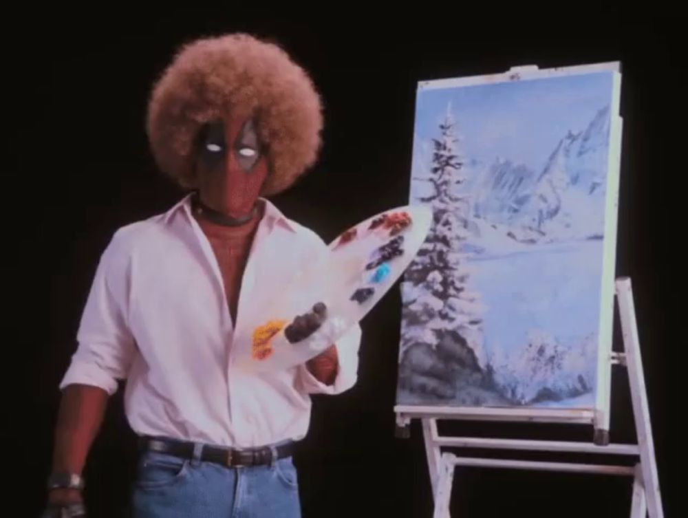 a man with a big afro is holding a palette in front of a painting