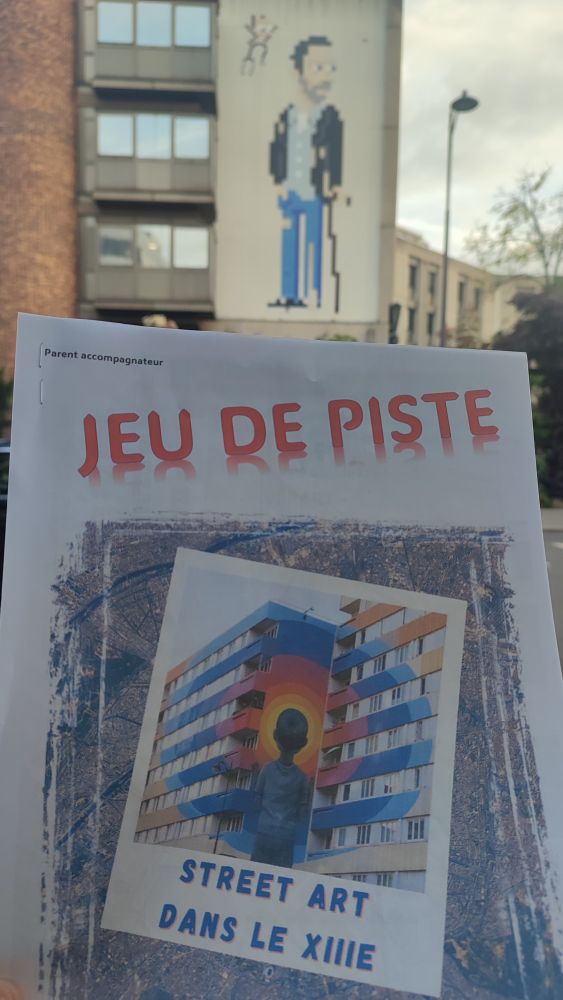 Au premier plan, le livret du jeu de piste sur le Street Art avec une œuvre de Seth qui se trouve sur le parcours. En arrière-plan, un Invader représentant le Docteur House.