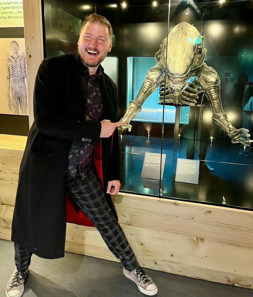 Smiling man pointing at a Xenomorph 