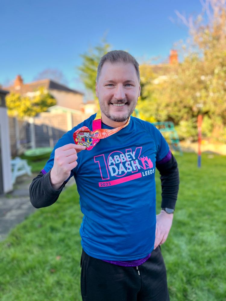 Smiling man in running outfit with a medal.
