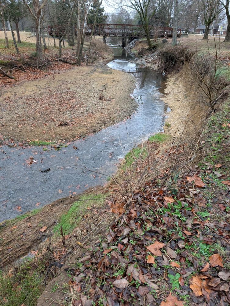 Same creek from previous image, in this one you can see a bridge over the creek and a neighborhood in the background 