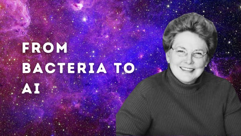 On the left in capitalised white text reads, 'From Bacteria to AI'. On the right there is a black and white photo of N. Katherine Hayles, a feminist philosopher of science. The background is a pink, blue and purple starry galaxy. 