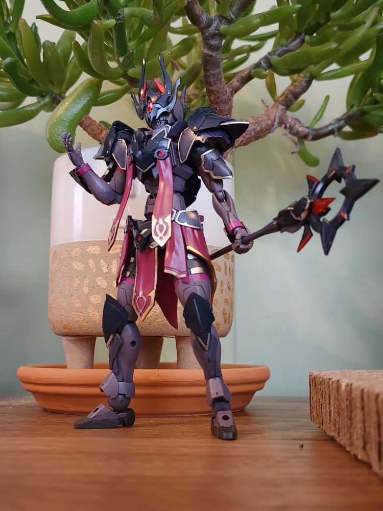 A completed model kit of the 30 Minutes Fantasy Rosan Bishop. The kit is in a standing pose facing the camera with its right arm bent with an outstretched hand and its staff in its right hand. My jade plant is in the background tee hee.