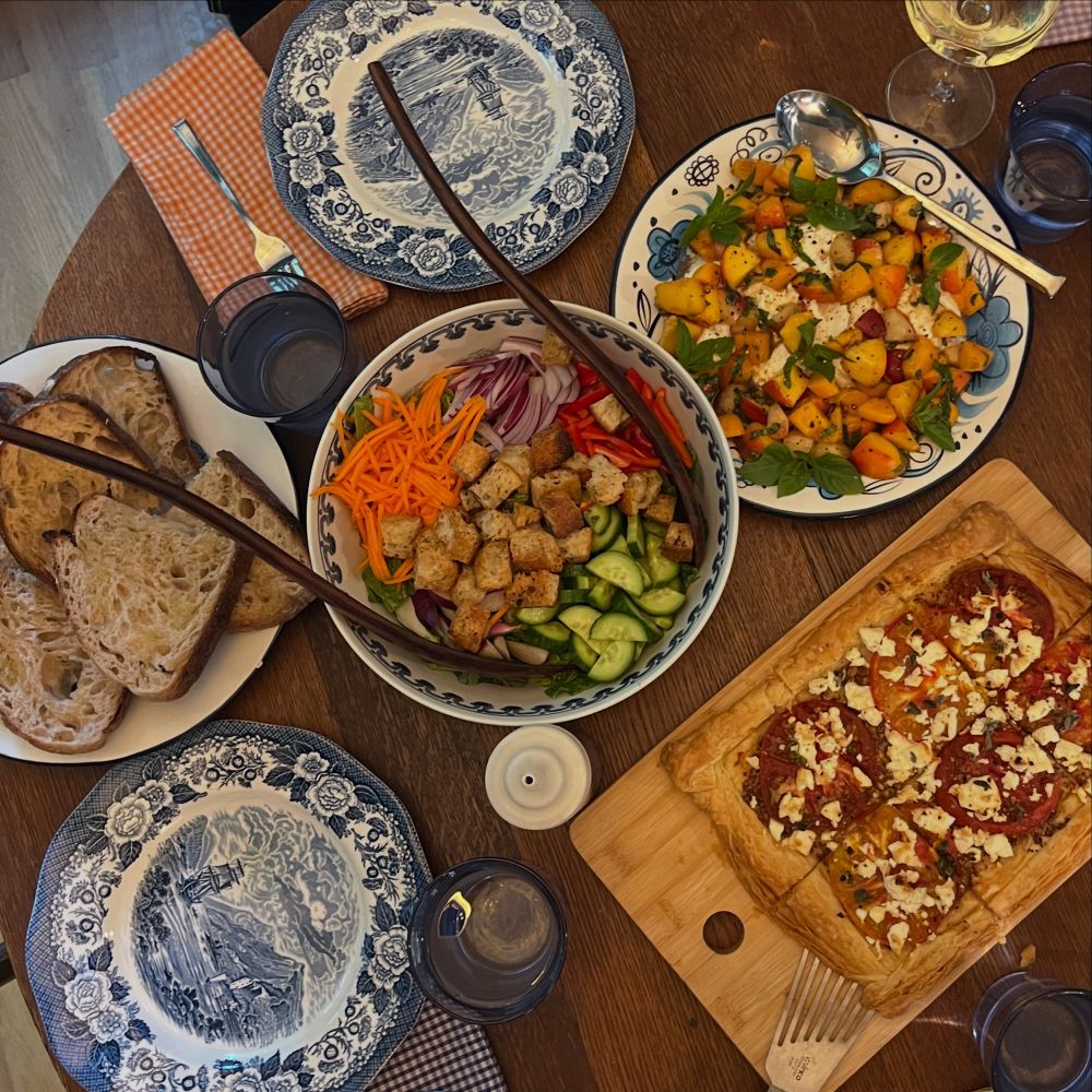 The table set with the food described above. It is crowded with server full of food and blue and white transferware plates.