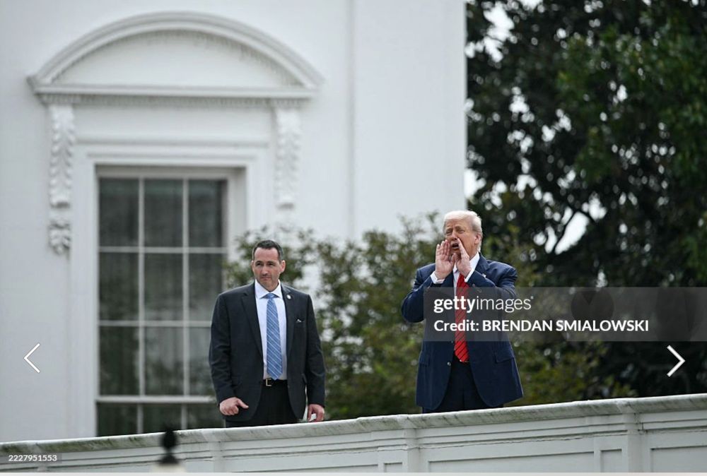Getty Images credit Brendan Smialowsky
Donald Trump stands on the roof of the white house with his hands cupped around his mouth hollering something while a secret service agent looks slightly perturbed.