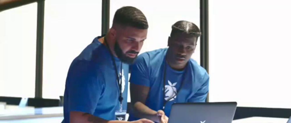 two men are looking at a laptop together .