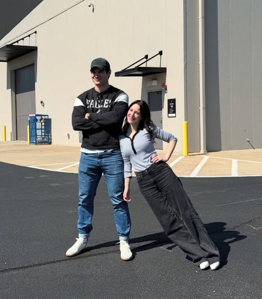David Corenswet wearing an Eagles sweatshirt with Rachel Brosnahan leaning on him 