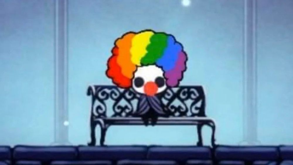 The knight from Hollow Knight sits on a bench, but they have a red clown nose and a multicolored clown wig.
