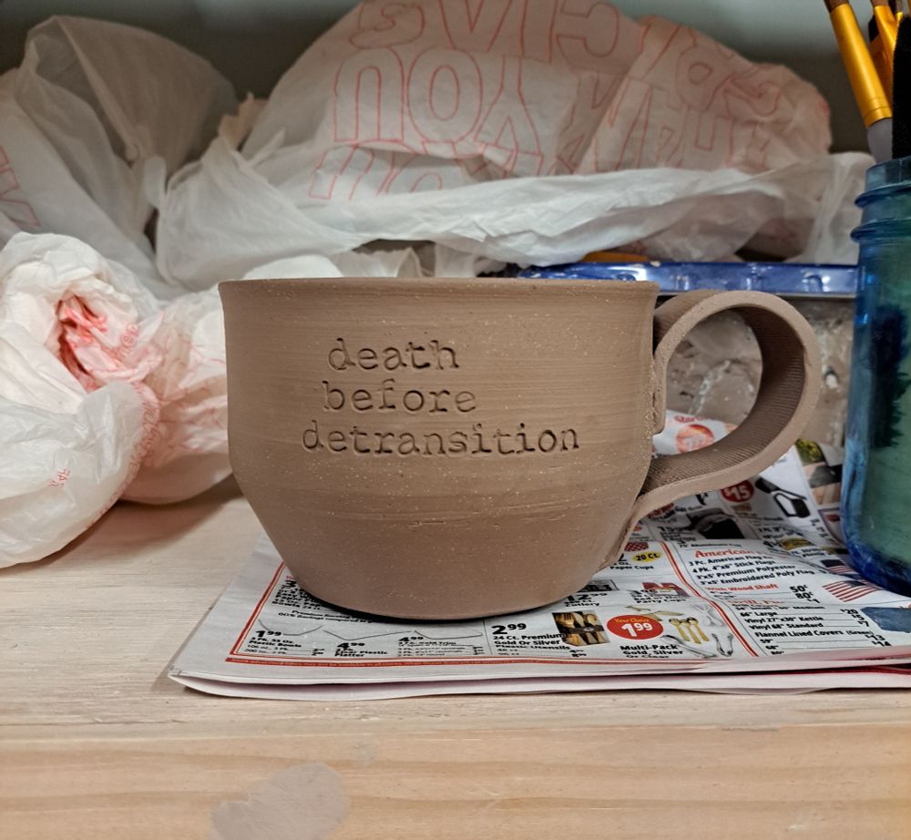 Unfired ceramic mug stamped with "death before detransition"