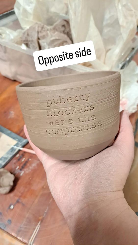 Unfired ceramic vessel with "puberty blockers were the compromise" stamped on the side