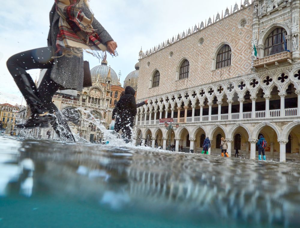 People walking through floodwater outside the Doge's palace in Venice, Italy. Source of photo is Adam Sébire / Climate Visuals.