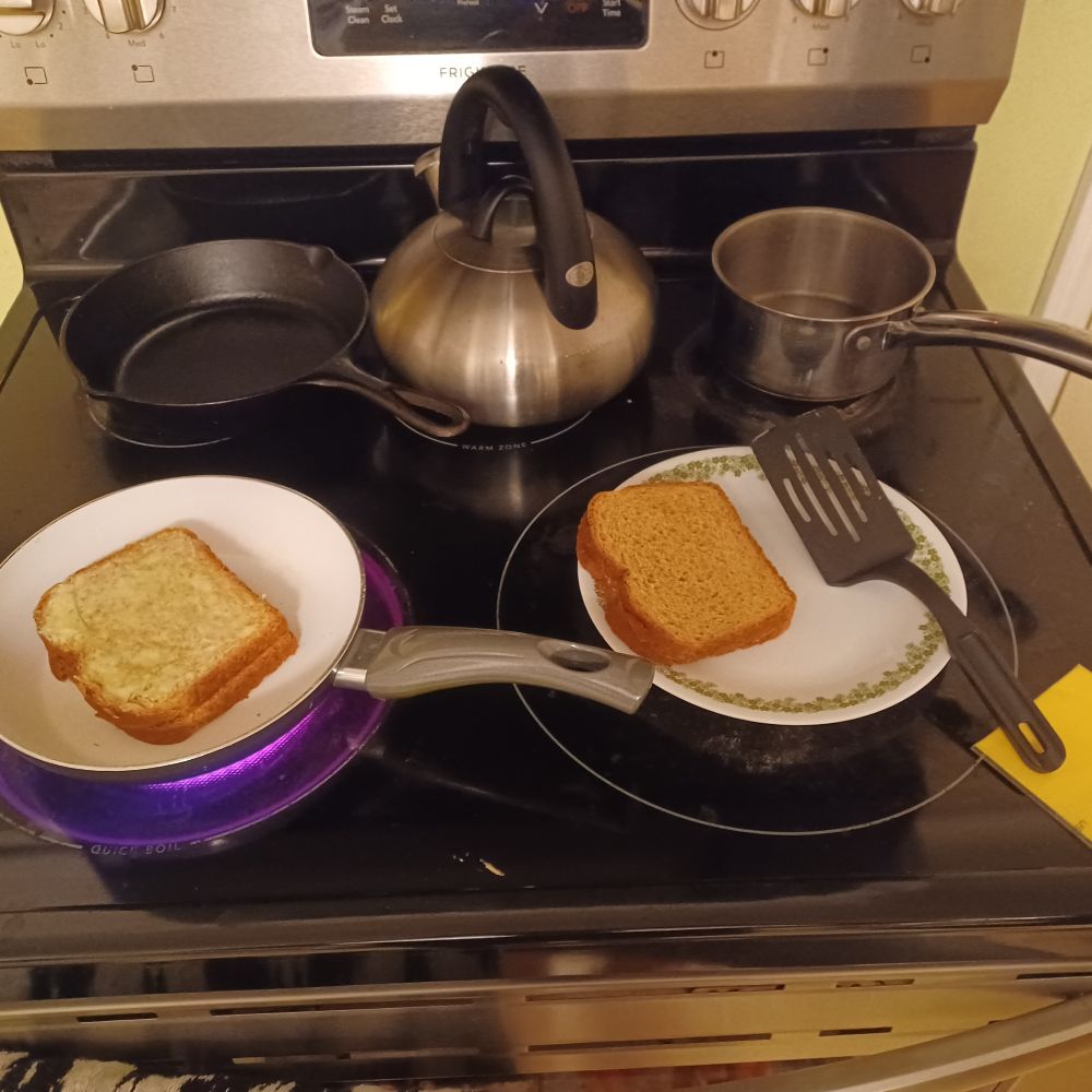 The grilling of a cheese, and fixings for a second one, on an electric range.