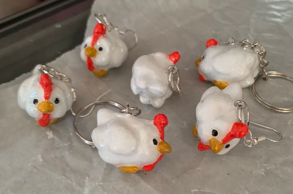 2 chicken keychains and 2 pairs of chicken earrings. The chicken is white with a yellow-brown beak and red thing thats on its head and chin. The design is based on the Hen Hens from Slime Rancher