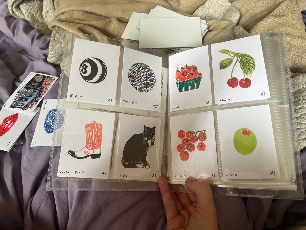 Photo of a clear trading card binder containing 8 Ana Inciardi prints 